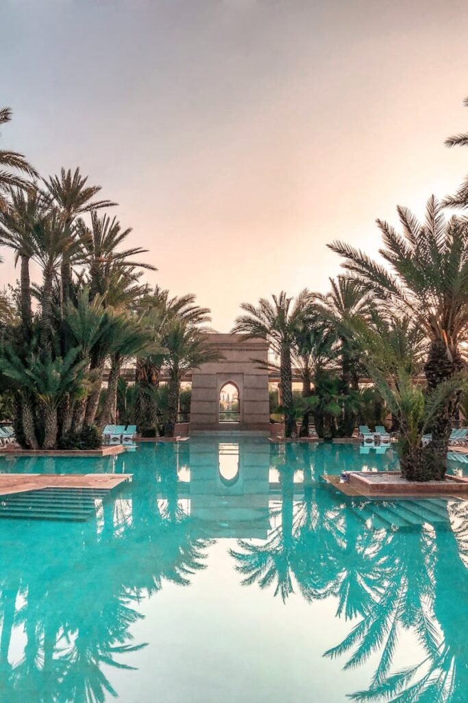 Idyllic tropical resort pool with palm trees reflecting at sunset.